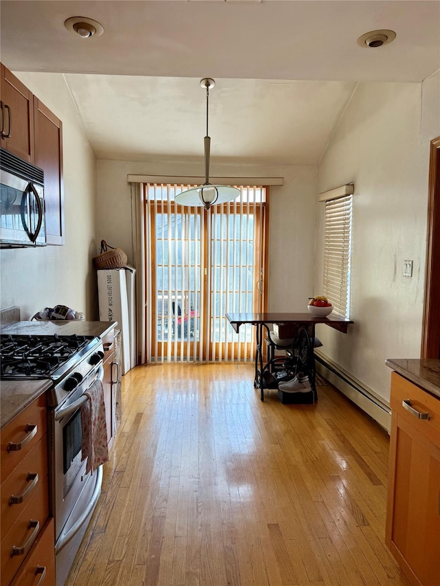 kitchen featuring appliances with stainless steel finishes, lofted ceiling, a baseboard radiator, brown cabinets, and light wood finished floors