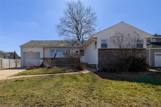 view of front of home with concrete driveway, an attached garage, a front lawn, and fence