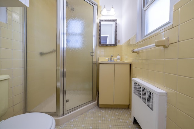 bathroom featuring toilet, tile walls, a shower stall, tile patterned floors, and radiator