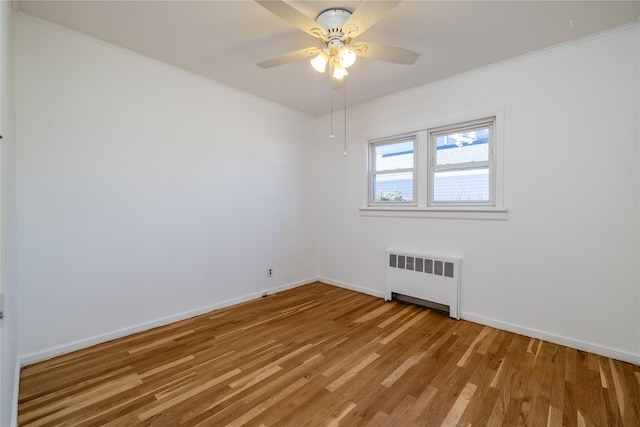 unfurnished room featuring radiator, light wood finished floors, baseboards, and crown molding