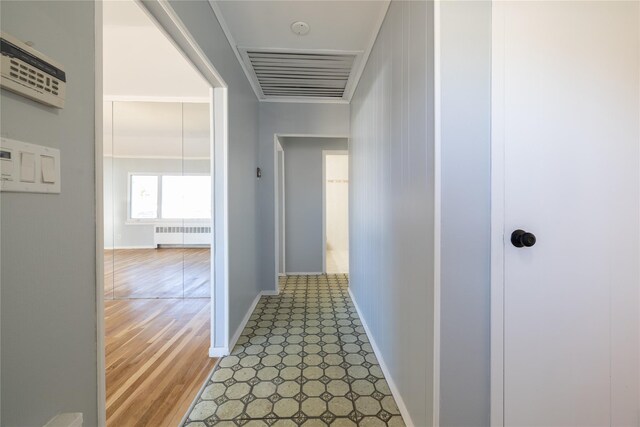 corridor with baseboards, visible vents, and radiator