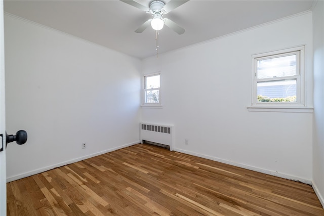 empty room with baseboards, ornamental molding, wood finished floors, and radiator