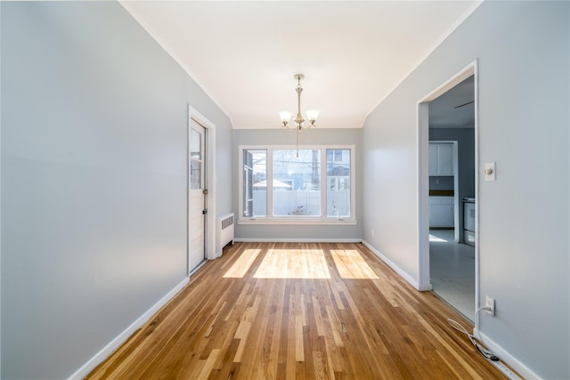 unfurnished dining area featuring radiator, an inviting chandelier, baseboards, and wood finished floors