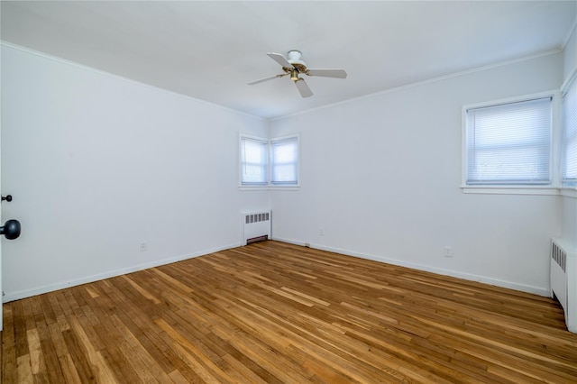 spare room featuring ornamental molding, radiator, baseboards, and hardwood / wood-style floors