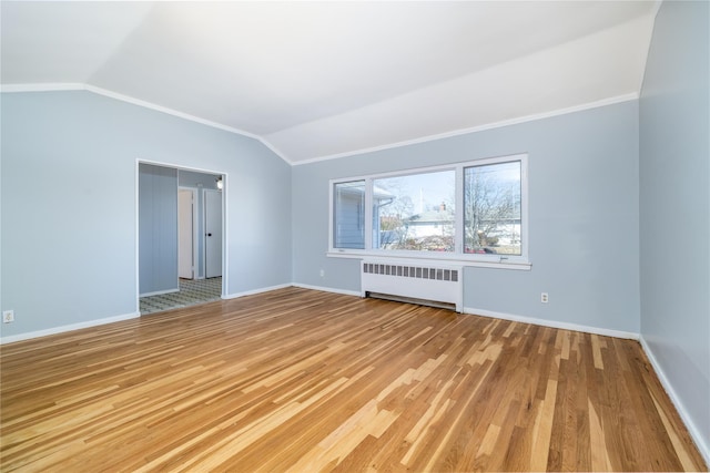 unfurnished room featuring lofted ceiling, radiator, light wood-style flooring, and baseboards