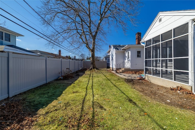 view of yard with a sunroom and a fenced backyard