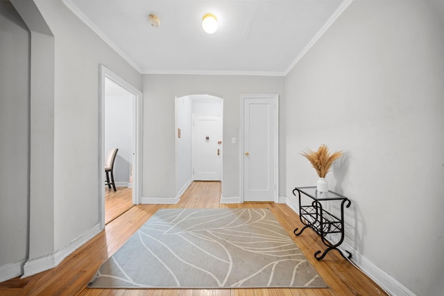 interior space with ornamental molding, arched walkways, baseboards, and wood finished floors