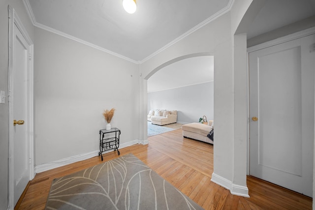 bedroom with ornamental molding, arched walkways, baseboards, and wood finished floors