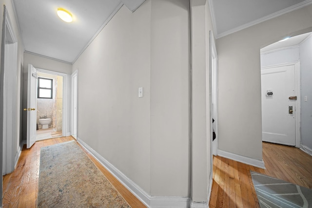 hall featuring baseboards, ornamental molding, and wood finished floors