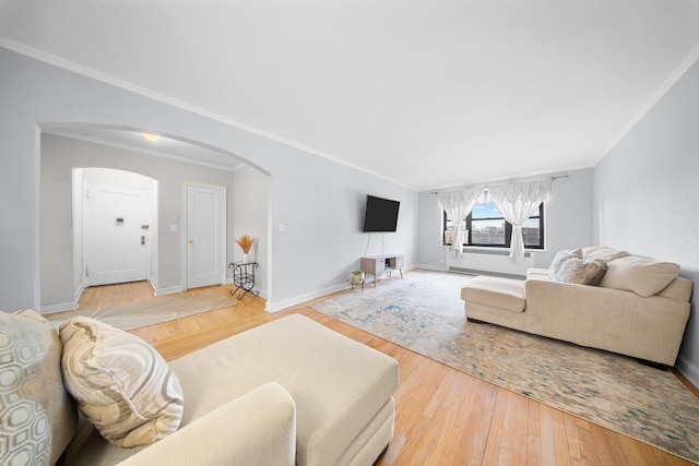 living area featuring light wood-style floors, arched walkways, crown molding, and baseboards