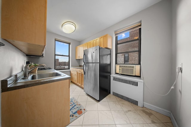 kitchen with radiator, freestanding refrigerator, cooling unit, light brown cabinetry, and a sink