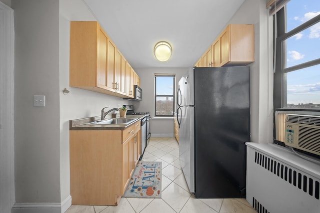 kitchen featuring light tile patterned floors, stainless steel appliances, radiator, light brown cabinetry, and a sink