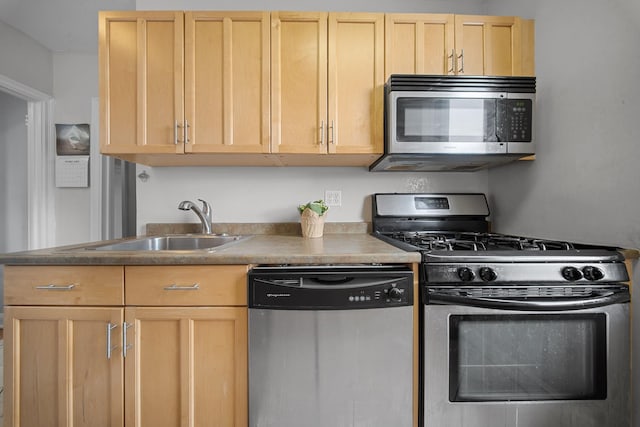 kitchen featuring appliances with stainless steel finishes, a sink, and light brown cabinetry