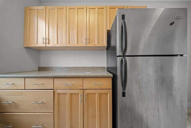 kitchen with freestanding refrigerator and light brown cabinetry