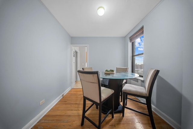 dining space with light wood-type flooring and baseboards