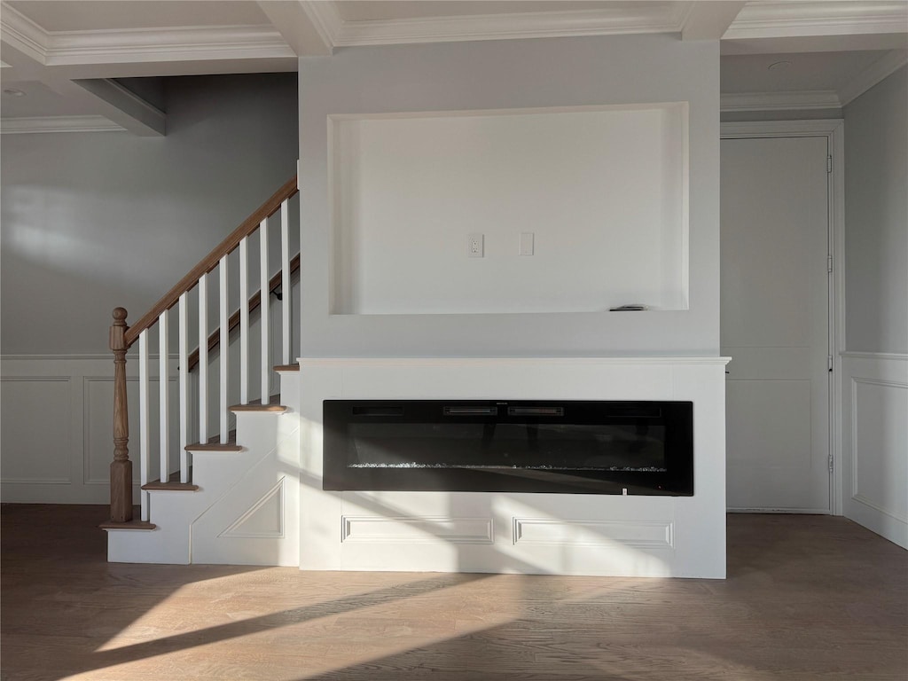 room details with crown molding, a decorative wall, wood finished floors, and a glass covered fireplace