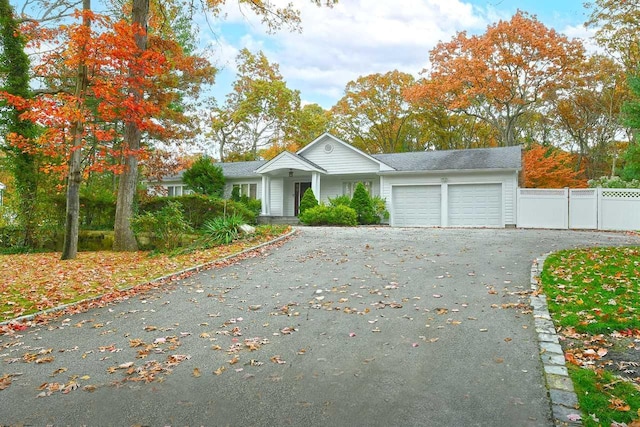 ranch-style home featuring a garage, fence, and aphalt driveway