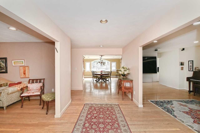 hall with baseboards, recessed lighting, a notable chandelier, and light wood-style floors