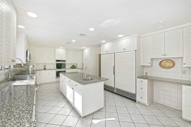 kitchen with light tile patterned floors, stainless steel appliances, tasteful backsplash, visible vents, and a sink