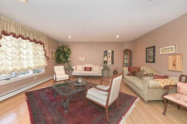 living room featuring light wood-style flooring, arched walkways, baseboard heating, and recessed lighting