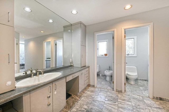 bathroom featuring marble finish floor, recessed lighting, toilet, a bidet, and baseboards