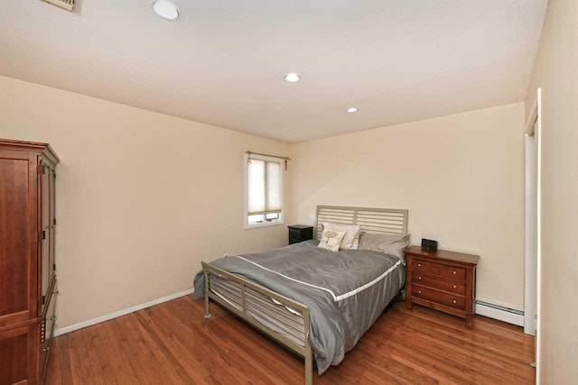 bedroom with a baseboard heating unit, recessed lighting, wood finished floors, and baseboards