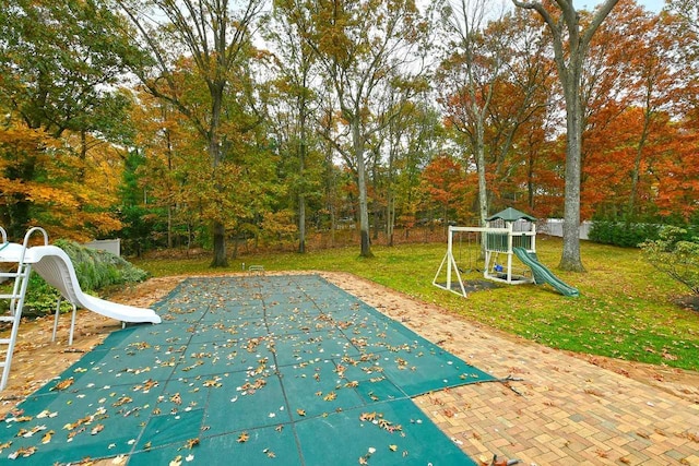 view of swimming pool with a playground and a yard