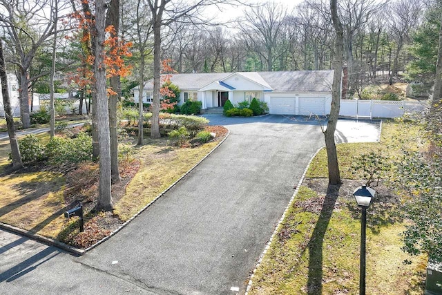 ranch-style house with aphalt driveway, a garage, and fence