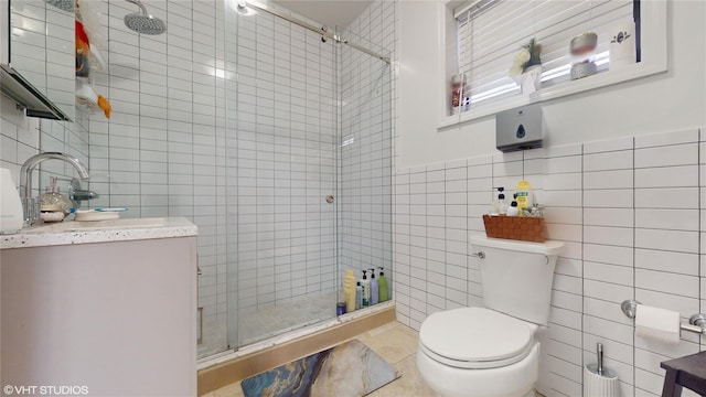 bathroom featuring toilet, vanity, a shower stall, and tile walls