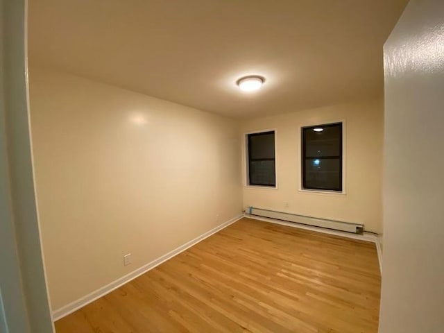 empty room featuring light wood-style floors, baseboards, and a baseboard heating unit