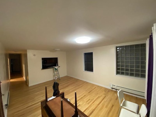 workout area featuring a baseboard heating unit, baseboards, and wood finished floors