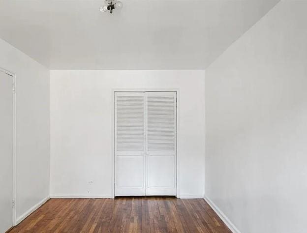 unfurnished bedroom with a closet, wood finished floors, and baseboards