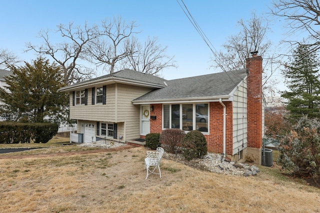 split level home with an attached garage, brick siding, roof with shingles, a chimney, and a front yard