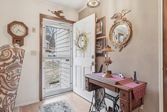 foyer entrance featuring baseboards, wood finished floors, and crown molding