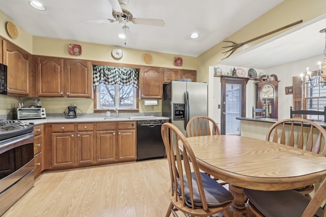 kitchen with brown cabinets, black appliances, light wood-style floors, and a sink