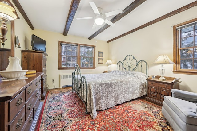 bedroom featuring ceiling fan, beamed ceiling, radiator heating unit, and wood finished floors