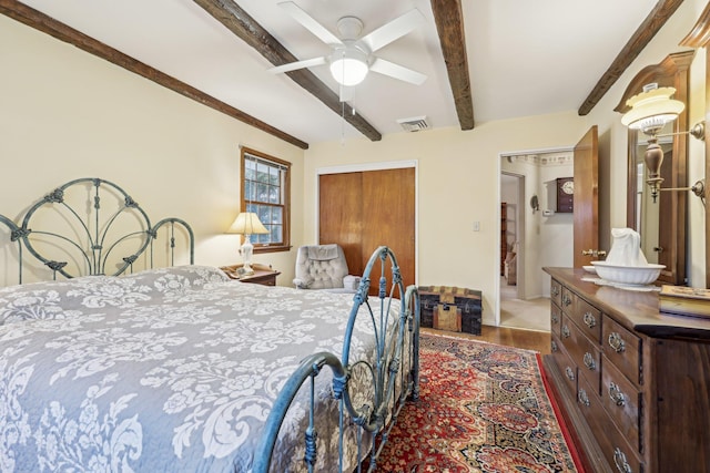 bedroom featuring wood finished floors, visible vents, a ceiling fan, a closet, and beamed ceiling