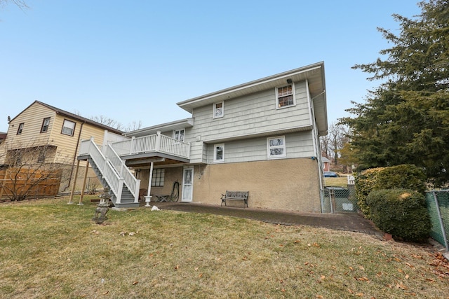 back of property featuring a lawn, a gate, fence, a deck, and stairs