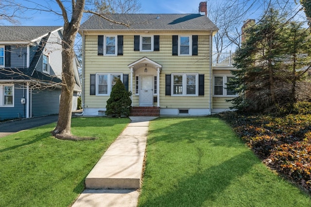 colonial inspired home with a front yard, roof with shingles, and a chimney