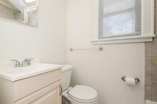 bathroom featuring toilet, a shower, and vanity