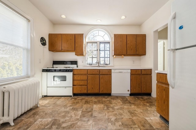 kitchen featuring white appliances, radiator heating unit, and brown cabinets