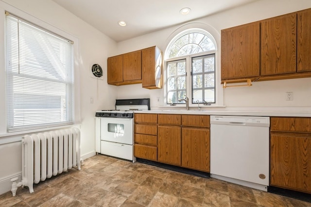 kitchen with white appliances, a sink, light countertops, brown cabinets, and radiator