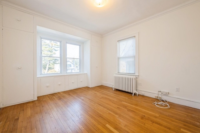 unfurnished room featuring crown molding, light wood finished floors, and radiator