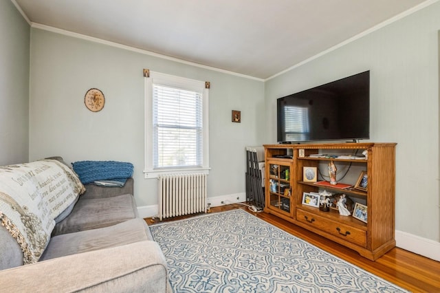 living area featuring baseboards, radiator heating unit, wood finished floors, and crown molding