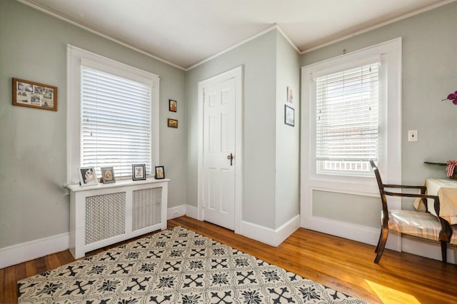 entrance foyer featuring light wood-style floors, radiator heating unit, ornamental molding, and baseboards