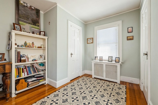 foyer entrance featuring crown molding, baseboards, and wood finished floors