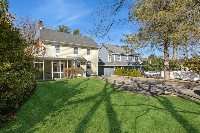 back of property featuring a sunroom, a yard, a chimney, and fence