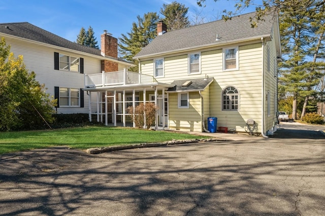 back of house featuring a balcony and a yard