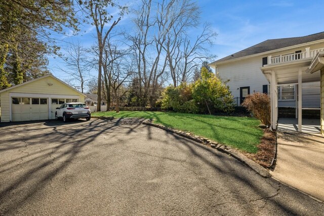 view of side of home featuring a yard, a detached garage, and an outbuilding