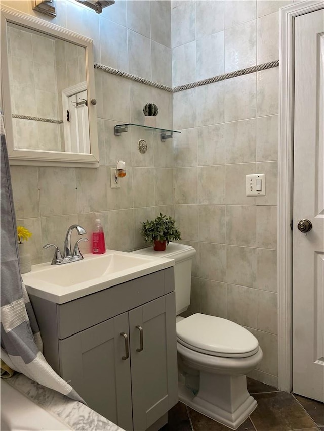 bathroom with toilet, tile patterned flooring, tile walls, and vanity